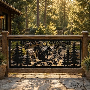 May include: A black metal railing insert featuring a laser-cut design of a squirrel perched on an oak branch with acorns, surrounded by pine trees and a sun. The rectangular panel is framed by wooden posts and set against a forest background.