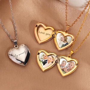 May include: Heart-shaped locket necklaces in silver and gold tones. The lockets open to reveal photos and the words "Love you" and "My sweetie" are engraved on the lockets. The necklaces are on a neutral background.