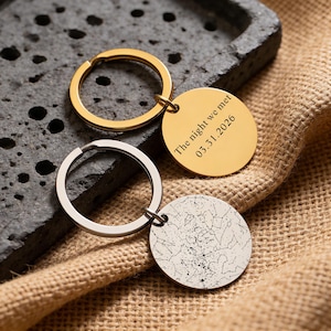 May include: Two keychains with round pendants. One gold keychain has a gold pendant with the text "The night we met 03.31.2026". The other keychain is silver with a pendant featuring a star map design.