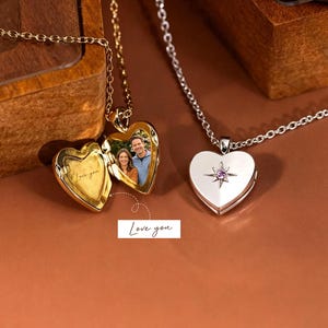Może przedstawiać: Dwa medaliony w kształcie serca na łańcuszkach. Jeden złoty medalion jest otwarty, ukazując zdjęcie pary oraz wygrawerowany napis "Love you". Drugi srebrny medalion jest zamknięty i posiada gwiazdkowy akcent z małym fioletowym kamieniem.