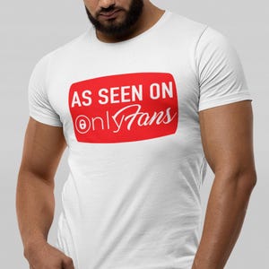 Puede incluir: Camiseta blanca con un gráfico rectangular rojo. El gráfico muestra el texto "AS SEEN ON OnlyFans" en blanco. La camiseta tiene mangas cortas y cuello redondo.
