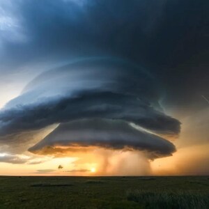 Puede incluir: Fotografía dramática de una tormenta supercelular. La imagen captura una gran y ominosa formación de nubes con una estructura rotatoria distintiva. Los rayos cruzan el cielo y el sol se pone en la distancia, iluminando el paisaje.