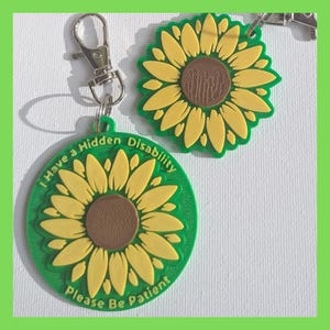 Puede incluir: Llavero de girasol verde y amarillo con el texto "I Have a Hidden Disability Please Be Patient".