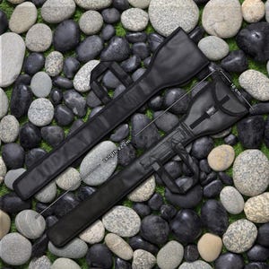 May include: Two black cases, likely for a long, slender item, are displayed. The cases are made of a smooth, matte material. One case has a handle and a buckle closure. The longer case is 92 cm in length, and the shorter case is 18 cm wide.
