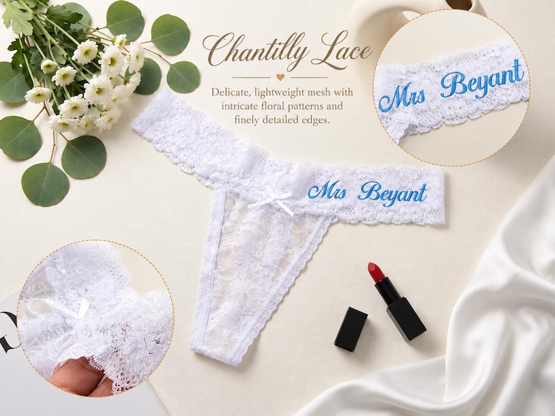 K&ouml;nnte beinhalten: Ein wei&szlig;er Spitzen-Tanga mit einer kleinen mittigen Schleife und dem in Blau gestickten Text Mrs Beyant. Das Kleidungsst&uuml;ck wird zusammen mit einem Strau&szlig; wei&szlig;er Blumen, einem roten Lippenstift und einem runden Ausschnitt gezeigt.