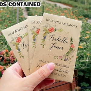 May include: Three brown paper packets with floral designs and the text "In Loving Memory Isabella Jones 10.03.19 05.12.2025 For our hearts Flower Seeds".