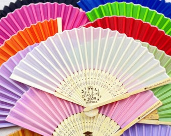 May include: A stack of colorful hand fans with wooden handles. The top fan has a white silk fabric with a personalized message that reads "Class of 2025 Sophia".