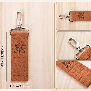 May include: A tan textured leather keychain with a silver metal swivel clasp. The keychain features a black engraved design of two crossed golf clubs, a golf ball, and the name Steven. It measures 4.5 inches in length and 1.5 inches in width.