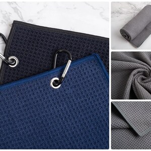 May include: Three microfiber towels with a waffle texture in black, blue, and gray. Each towel has a metal carabiner clip attached.
