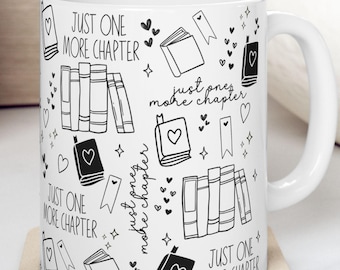 May include: White ceramic mug with a black and white design featuring books, hearts, and the text "JUST ONE MORE CHAPTER". The mug sits on a beige coaster.