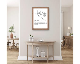 Könnte beinhalten: Ein gerahmter Druck mit einem schwarz-weißen grafischen Design des Wortes "LOVE" mit einer Definition darunter. Der Rahmen ist aus hellem braunem Holz.