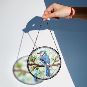 a hand holding a stained glass bird hanging from a chain
