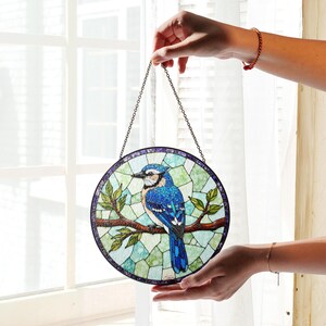 a hand holding a stained glass bird hanging from a chain