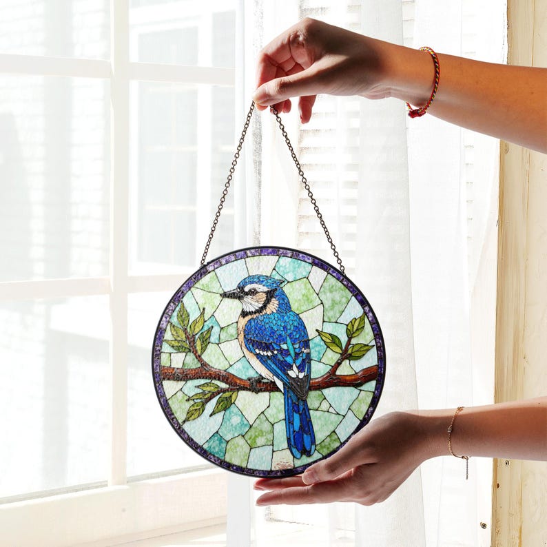 a hand holding a stained glass bird hanging from a chain