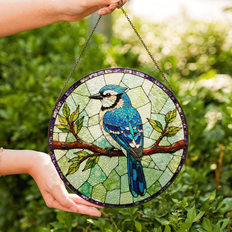 a hand holding a stained glass bird on a branch