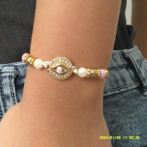 Bracelet artisanal œil protecteur doré – Perles nacrées et détails roses – Bijou porte-bonheur fait main cadeau parfait