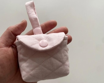 Può includere: Una piccola pochette trapuntata rosa chiaro con un motivo a cuciture a rombi. La pochette presenta una patta ripiegabile fissata con un bottone a pressione in plastica rosa chiaro abbinato e un manico in tessuto verticale con chiusura.