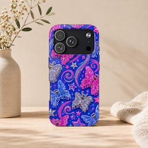 May include: A blue phone case with a butterfly and star pattern. The case features pink, blue, and silver butterflies, stars, and swirls. The phone case has a camera cutout at the top.