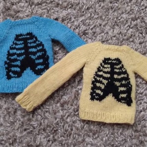 May include: Two knitted sweaters with a ribcage design. One sweater is light blue and the other is yellow.
