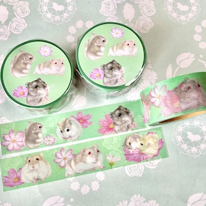 May include: Green washi tape rolls and strips with illustrations of hamsters and pink flowers. The tape rolls have a green background with hamster and flower designs. The strips show the same design.