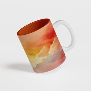 K&ouml;nnte beinhalten: Wei&szlig;e Keramiktasse mit einem farbenfrohen Sonnenuntergangsdesign. Die Tasse hat ein Aquarell-Design in Rot, Orange, Gelb und Lila.