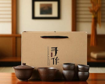 May include: A brown tea set with a lidded teapot, a small pitcher, and four teacups. The set is displayed in front of a brown paper gift box with Chinese characters. The tea set is on a wooden table.
