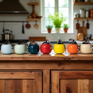May include: A collection of seven ceramic jars in various colors, including light blue, green, navy, red, yellow, orange, and cream. Each jar has a floral-patterned lid and a small handle. The jars are arranged on a wooden surface.