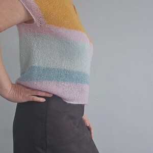 Può includere: Un top a maglia a righe con scollo a V e maniche corte. Il top è realizzato in un filato morbido e leggero e presenta uno schema di colori arcobaleno di giallo, rosa, azzurro e verde.