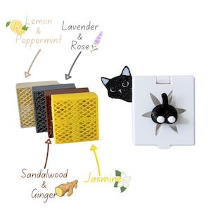 May include: Four different scented diffuser pads with a black cat peeking out from behind the yellow pad. The pads are labeled with the scents: Lemon & Peppermint, Lavender & Rose, Sandalwood & Ginger, and Jasmine.