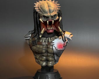 May include: A detailed bust of the Predator, a fictional alien hunter from the movie franchise. The bust is made of painted resin and features a detailed sculpt of the Predator's head, including its iconic mandibles, dreadlocks, and bio-mask. The bust is mounted on a black base.