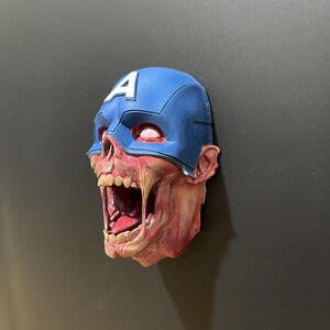 May include: A 3D printed zombie Captain America head with a blue and white helmet and a red, white, and blue costume. The head is open-mouthed and has a red, white, and blue tongue.
