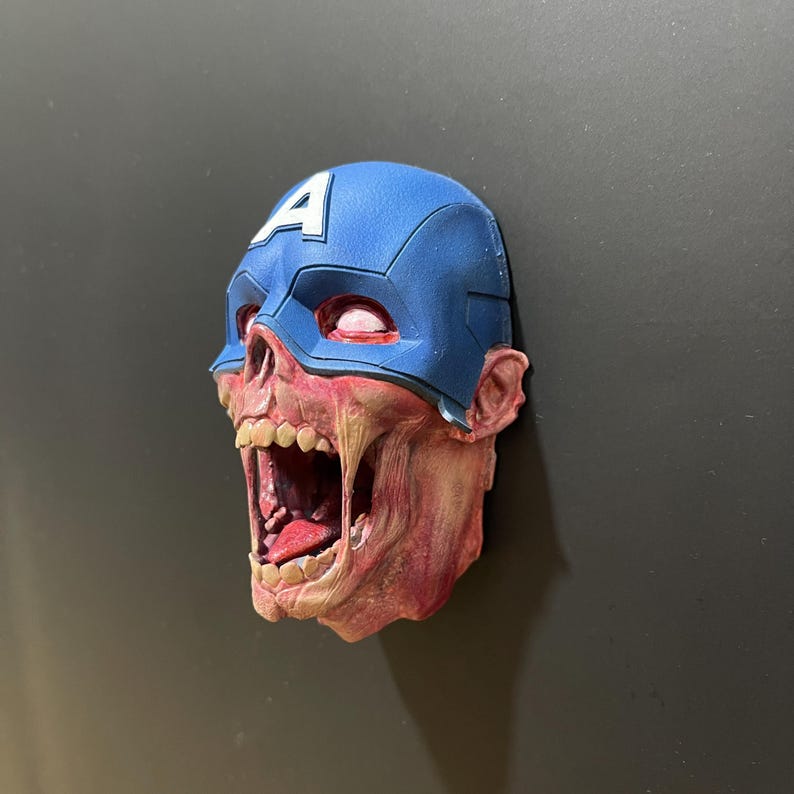 May include: A 3D printed zombie Captain America head with a blue and white helmet and a red, white, and blue costume. The head is open-mouthed and has a red, white, and blue tongue.