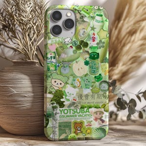 Könnte beinhalten: Grüne Handyhülle mit einer Collage aus Bildern, darunter Zeichentrickfiguren, Essen und japanischer Text. Die Hülle hat eine glänzende Oberfläche und einen Kameraausschnitt. Der Text "Yotsuba @Summer Vacation" ist sichtbar.