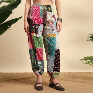 Könnte beinhalten: Bunte Patchworkhose mit weitem Schnitt und elastischen Knöcheln. Der Stoff weist eine Vielzahl von Mustern auf, darunter Blumen- und geometrische Designs. Die Farben umfassen Rosa, Grün und Blau.