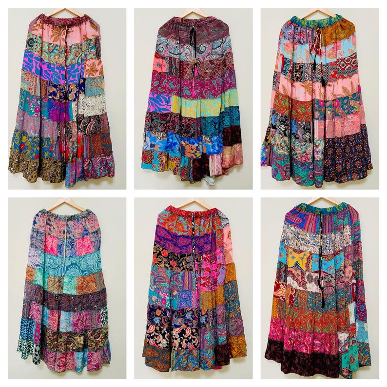 Puede incluir: Seis faldas patchwork coloridas, compuestas por diversos patrones y colores de tela, incluyendo rosa, morado, azul y naranja. Las faldas est&aacute;n colgadas en perchas de madera sobre un fondo blanco. Las faldas tienen un dise&ntilde;o escalonado.