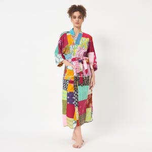 May include: A long-sleeved robe featuring a vibrant patchwork design with various colorful patterns including floral, geometric, and abstract prints in shades of red, yellow, blue, green, and pink, complete with a matching fabric tie belt at the waist.