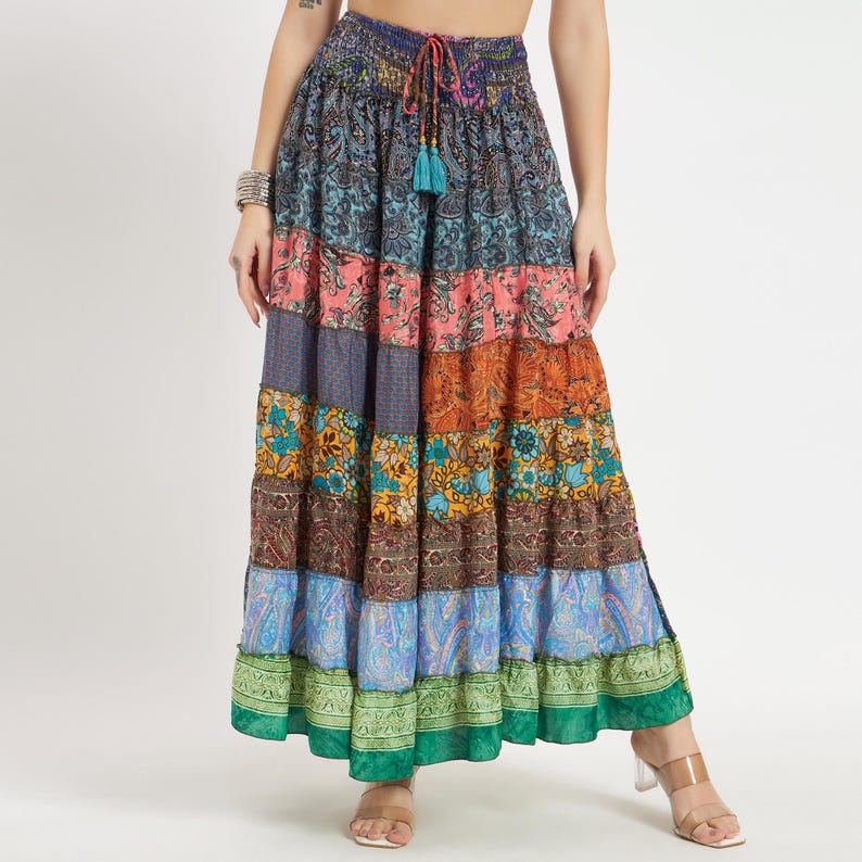 May include: A long, tiered skirt with a patchwork design. The skirt features a variety of colors and patterns, including paisley, floral, and geometric prints. It has a drawstring waist and a tassel detail. The skirt is made of a lightweight fabric.