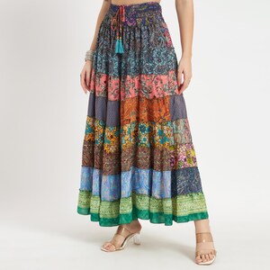 May include: A patchwork maxi skirt with a drawstring waist. The skirt features a variety of patterned fabrics in shades of blue, pink, orange, and green. The skirt has a tiered design and a flowing silhouette.