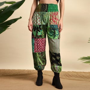 Könnte beinhalten: Patchworkhose mit einer Mischung aus grün, roten und schwarzen gemusterten Stoffen. Die Hose hat eine hohe, elastische Taille und Taschen. Die Knöchel sind gerafft, und die Hose wird mit schwarzen Stiefeln getragen.