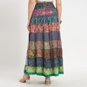 May include: A long, patchwork skirt with a tiered design. The skirt features a variety of colorful paisley and floral patterns in shades of blue, pink, green, and brown. The skirt is made of a lightweight fabric and has an elastic waistband.