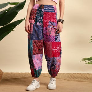 Peut inclure: Pantalon patchwork multicolore, ample et confortable, avec chevilles élastiquées. Le design présente divers motifs dans des tons de rose, rouge, bleu et vert. Le pantalon est doté de poches et est fait de tissus à motifs variés.