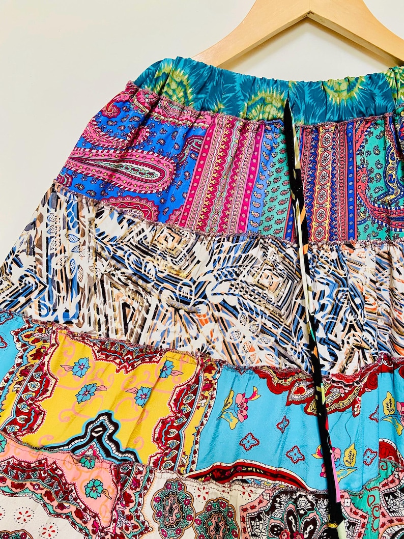 Puede incluir: Falda patchwork colorida con una variedad de patrones y colores, incluyendo dise&ntilde;os de cachemira y florales. La falda tiene una cintura con cord&oacute;n y una mezcla de colores vibrantes como azul, rosa, amarillo y turquesa.