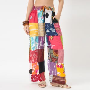 Può includere: Pantaloni a gamba larga con un vivace design patchwork caratterizzato da vari motivi floreali, a righe e geometrici nei toni del rosso, giallo, blu, bianco e nero. I pantaloni presentano una vita elasticizzata con coulisse e tasche laterali.