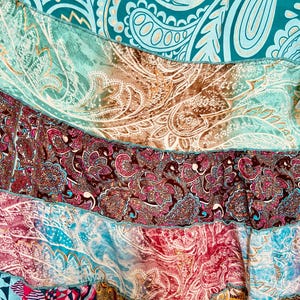 Puede incluir: Primer plano de un textil patchwork con una variedad de estampados de cachemira y geom&eacute;tricos. La tela presenta tonos de verde azulado, marr&oacute;n, rosa y rojo, con una mezcla de texturas y dise&ntilde;os. El textil parece ser una falda o una prenda similar.