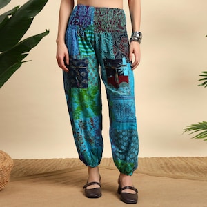 Könnte beinhalten: Patchworkhose in Blau-, Grün- und Lilatönen. Die Hose hat eine Mischung aus gemusterten Stoffen, darunter Paisley- und Blumendesigns. Sie hat zwei Vordertaschen und einen elastischen Bund. Die Hose wird mit braunen Schuhen getragen.