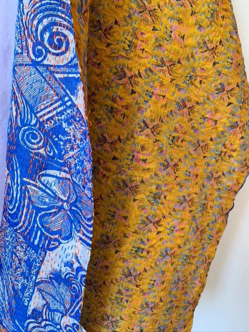 May include: Close-up of two fabric panels. One panel is blue with white floral and geometric patterns. The other panel is yellow with a repeating pattern of small, dark shapes and flecks of blue and pink.