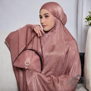 May include: A rose gold prayer shawl with a scalloped edge and a matching rose gold bag with a jeweled clasp. The bag has a black lining.