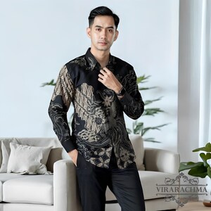May include: A black long-sleeved shirt with a beige and black batik pattern. The shirt has a button-down collar and a button-up front.