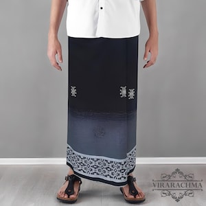 May include: A black and blue sarong with a geometric pattern at the bottom and decorative white designs. The sarong has a gradient effect, transitioning from black to blue. The bottom border features a white and gray geometric design.