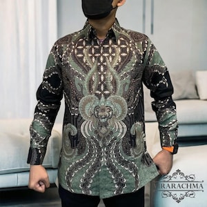 May include: A long-sleeved shirt with a green and black batik pattern. The pattern features a large, intricate design with a floral motif.